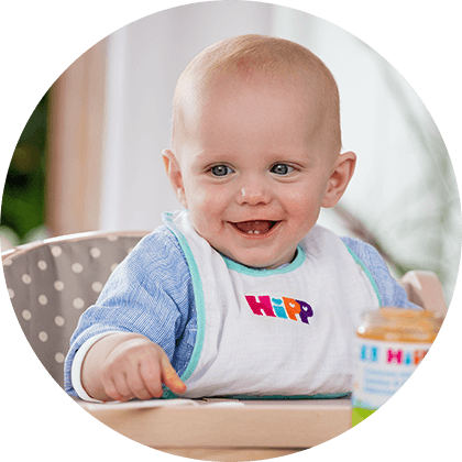 A baby in a high chair with a bib and a jar of food.