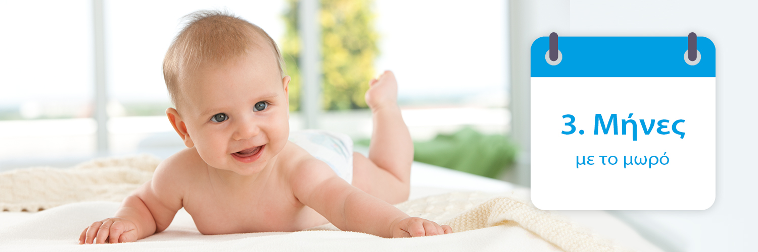 Ένα μωρό κείτεται σε ένα κρεβάτι, κοιτάζοντας προς τα εμπρός, με ένα ημερολόγιο στα δεξιά του που αναγράφει την ημερομηνία "3. Μάρτης" στα ελληνικά.
